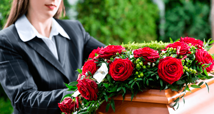 mulher ao lado de um caixão coberto de rosas em um funeral